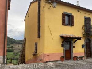 a yellow building with a door and a window at Casa vacanze Il Geranio in Celleno +6 photos