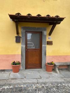 une porte d'un bâtiment avec deux plantes et un banc dans l'établissement Casa vacanze Il Geranio, à Celleno