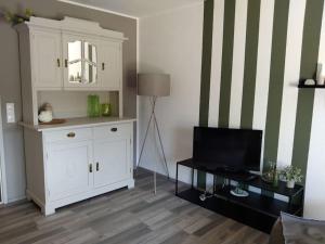 Liebevoll eingerichtete Wohnung في رانكفايل: غرفة معيشة مع خزانة بيضاء وتلفزيون