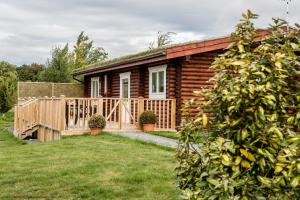 um chalé de madeira com uma cerca de madeira e um quintal em Teal Lodge - Nordic Log Cabin with private hot tub em Selby