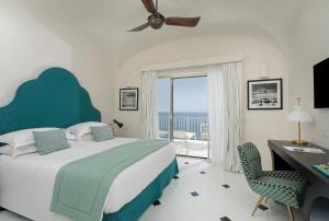 a bedroom with a bed and a desk and a window at Hotel Miramalfi in Amalfi