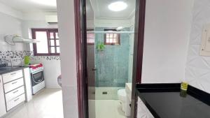 ein Badezimmer mit einer Dusche mit einer Glasdusche an der Hintertür in der Unterkunft Condominio Village Americana in Ubatuba