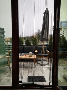 eine offene Glastür mit einem Sonnenschirm auf dem Balkon in der Unterkunft Silver Mountain B12 in Poiana Brașov