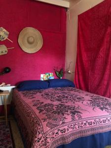 a bedroom with a pink wall and a bed with a hat on it at BnB SoMom Mobay Lodging in Montego Bay