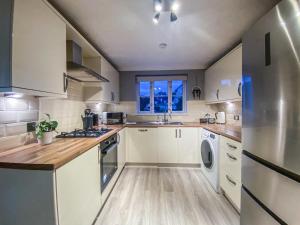 a kitchen with white cabinets and a window at 3 Bedroom House by Elegance Living in Peterborough