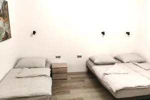 Dom gościnny 4 JAWA II في Tuczempy: سريرين في غرفة بجدران بيضاء وأرضية خشبية