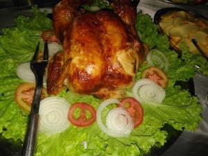 a chicken on a plate with lettuce and tomatoes at POUSADA MINEIRA in Águas de São Pedro