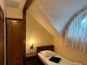 a small bedroom with a bed and a window at Restauracja i Hotel Oberża Wilczy Głód in Krzyszkowice