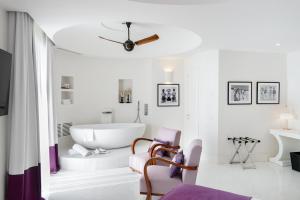 a white bathroom with a tub and a chair at Hotel Miramalfi in Amalfi