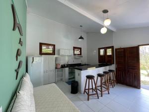 a kitchen with a refrigerator and bar stools in it at DECK HOUSE in Tatajuba