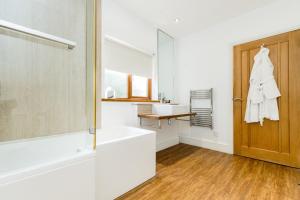 uma casa de banho com uma banheira, um lavatório e um espelho. em The Gower Hotel em Swansea