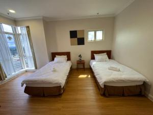 two beds in a room with two windows at StayInn Gateway Hotel Apartment, 2-bedroom Kuching City PrivateHome in Kuching