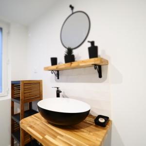 La salle de bains est pourvue d'un lavabo noir et d'un miroir. dans l'établissement NOUVEAUTE 2024 Appartement Design avec jardin, à Bellerive-sur-Allier