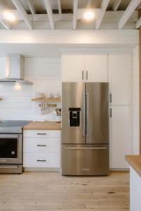 a kitchen with a stainless steel refrigerator and white cabinets at Villa Marguerita by WB Abodes in Wrightsville Beach