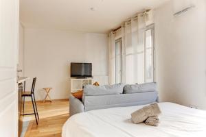 ein weißes Zimmer mit einem Sofa und einem Bett in der Unterkunft Le Curie - Saint Cyr in Saint-Cyr-lʼÉcole