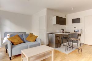 a living room with a couch and a kitchen at Le Curie - Saint Cyr in Saint-Cyr-lʼÉcole