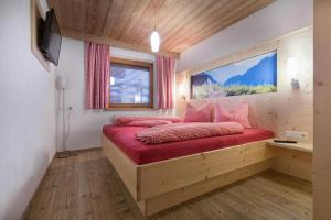 Un dormitorio con una gran cama de madera con almohadas rojas en Bergsonnhof en Jerzens