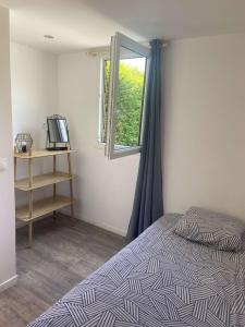 um quarto com uma cama e uma janela em Gite proche Côté fleurie em Martainville