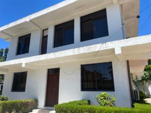 a white house with black windows and a door at Luxurious apartment with King size bed in Dar es Salaam