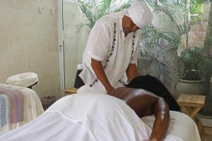 a woman in a white dress cutting a mans hair at Coco Unlimited in Tulum