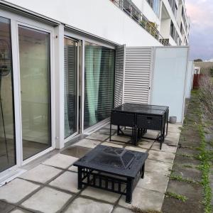 een patio met een tafel en banken op een balkon bij Appart Cosy Rennes Courrouze, 5min métro. in Saint-Jacques-de-la-Lande