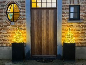 due alberi di Natale davanti a una porta di legno di Het Herenhuis a Genk