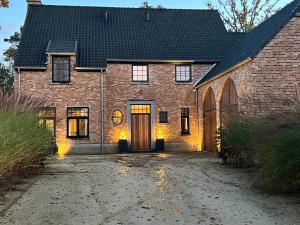 a brick house with two doors and a driveway at Het Herenhuis in Genk