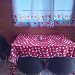 a red and white table with chairs and a curtain at Cabaña Cachi in Cachí