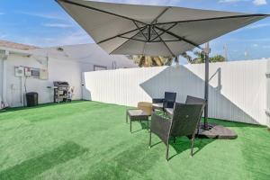 a patio with an umbrella and chairs on a lawn at Luxury Private Studio + Backyard in Naples
