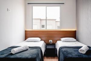 two beds in a room with a window at Apartamento Autódromo de Interlagos sp in Sao Paulo