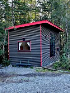 a small cabin with a red roof in the woods at Molco Cabins Loft in Pucón