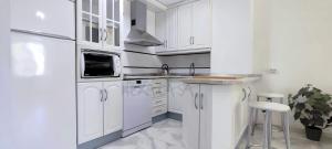 a white kitchen with a sink and a refrigerator at Laguna Green Apartment in Torrox Costa