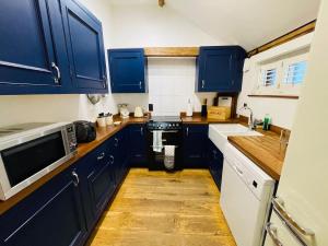 a blue kitchen with blue cabinets and a sink at Stable Cottage at Lee Wick Farm Cottages & Glamping in Clacton-on-Sea