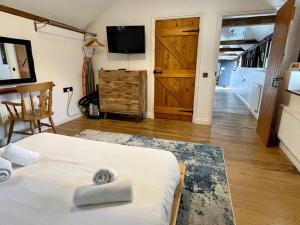 a room with a bed and a television and a door at Stable Cottage at Lee Wick Farm Cottages & Glamping in Clacton-on-Sea
