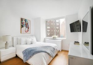 um quarto branco com uma cama e uma janela em Stylish 2 BD 2 BA At UES em Nova York