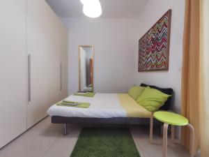 um pequeno quarto com uma cama e um banco verde em ZagHouses - sea view apartments in Sicily em Agnone Bagni