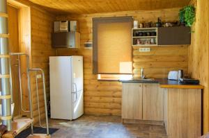 a kitchen with a white refrigerator in a wooden cabin at Grāveri kempings in Usma