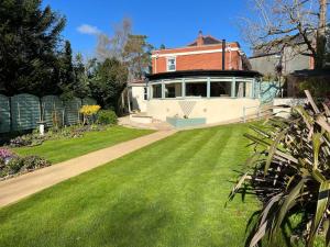 una casa con un césped verde delante de ella en Osmund House, Salisbury Sleeps up to 19 en Salisbury