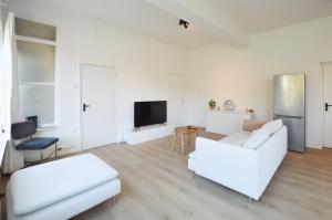 a living room with white furniture and a flat screen tv at Boutique Appartement Oost in Nijmegen