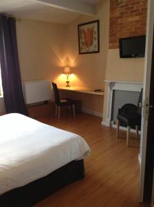 1 dormitorio con cama, escritorio y chimenea en Hôtel Restaurant de la Place, en Saint-Jean-dʼAngély