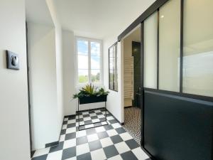 a hallway with a black door and a checkered floor at Le Petit Rousseau - Maison Climatisé - Classé 4 ETOILES in Hurigny