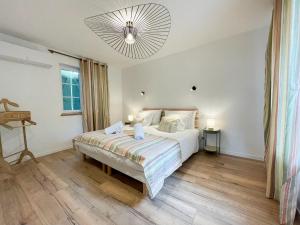 a bedroom with a bed and a chandelier at Le Petit Rousseau - Maison Climatisé - Classé 4 ETOILES in Hurigny