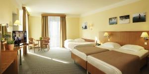 a hotel room with two beds and a table at Hotel Neptun - Terme & Wellness Lifeclass in Portorož