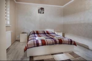 een witte slaapkamer met een bed met een geruite deken bij Апарт-готель Уляна in Skhidnitsa