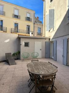a patio with a table and chairs and buildings at Grand appartement de 100M2 -Allée Paul Riquet Béziers - 4chambres - Wifi- Tv connectée in Béziers