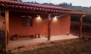 伊比科阿拉Vila Sincorá - Chalé para 4 pessoas com cozinha a 2 km da portaria da Cachoeira do Buracão的前面有长凳的小房子