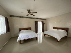 een slaapkamer met 2 bedden en een plafondventilator bij Mexhe Hotel El Cuyo in El Cuyo