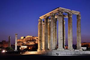 Un antiguo templo con columnas en una ciudad por la noche en Acropolis penthouse with breathtaking city view en Atenas