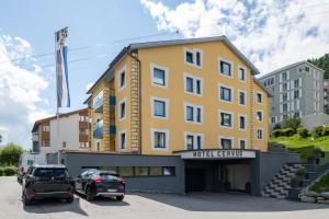 um edifício amarelo com carros estacionados num parque de estacionamento em Boutique Hotel Cervus em St. Moritz