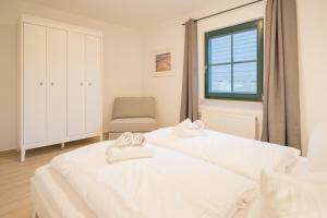 two beds in a room with a chair and a window at Ferienwohnung Lee West 2 2 in Dierhagen
